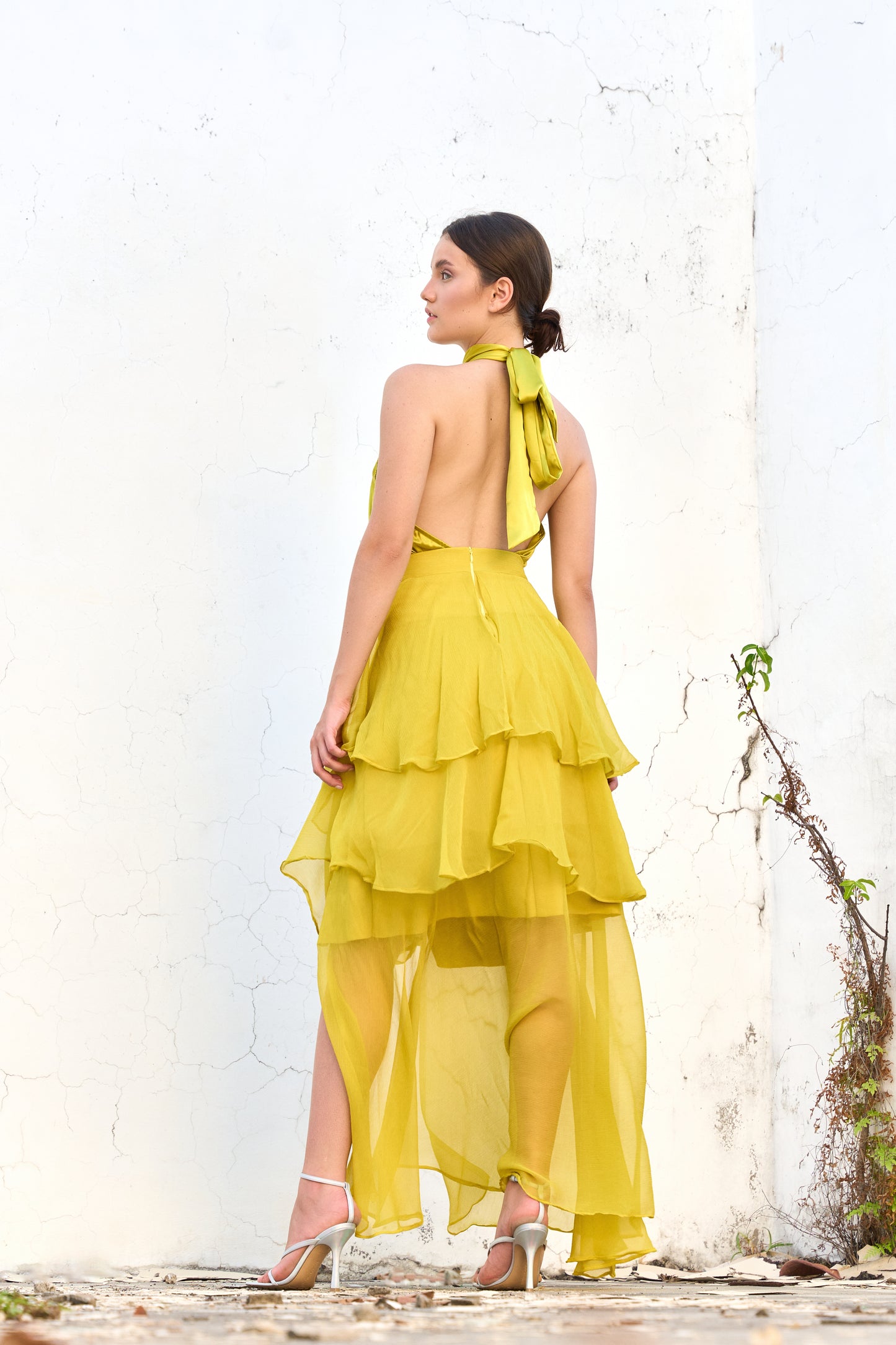 A model wearing a yellow skirt with ruffles and a slit by Monica Arguedas.