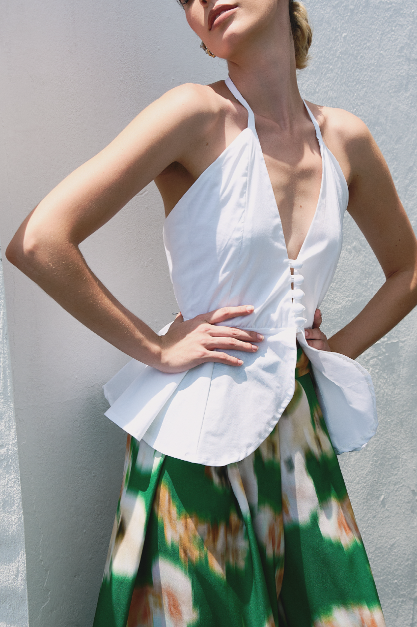 A model wearing a white top with bottons and ruffles by Monica Arguedas