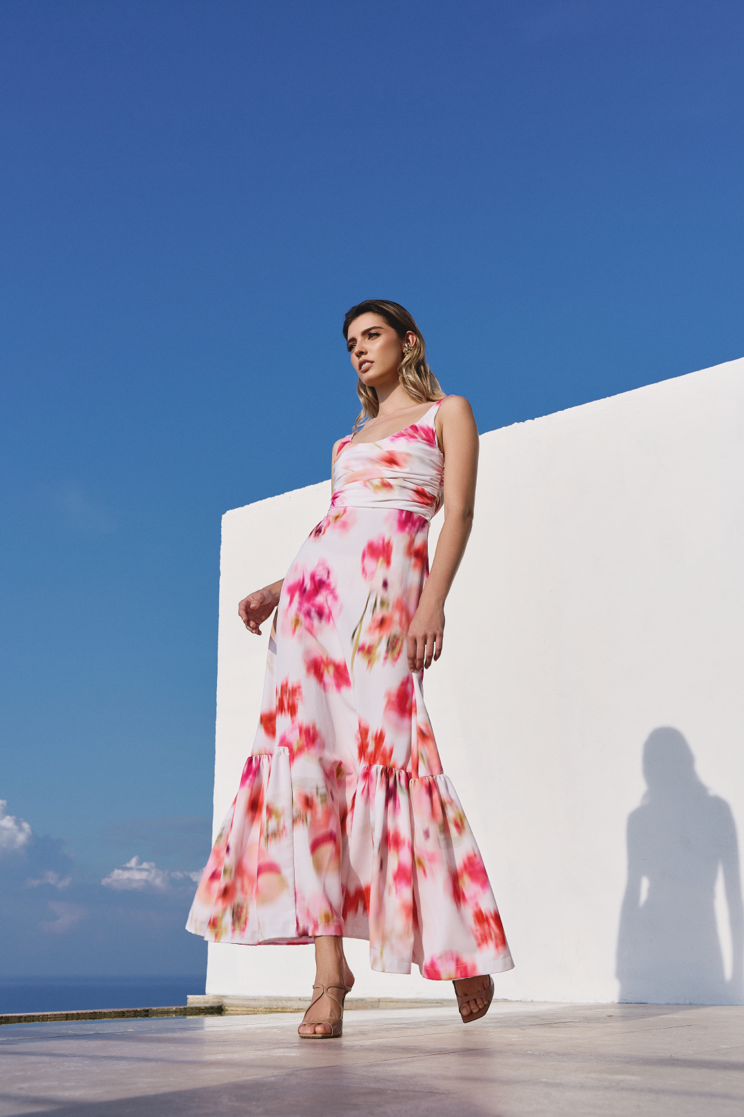A model wearing a white scrunched dress with a blurred floral print by Monica Arguedas.