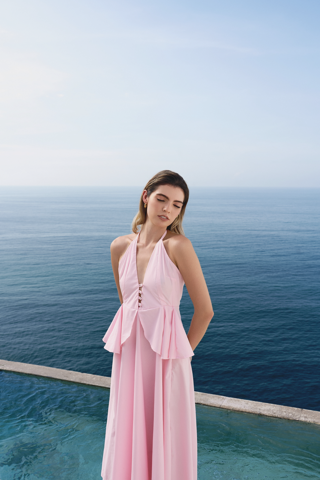 A model wearing a baby pink flowy dress with ruffles by Monica Arguedas.