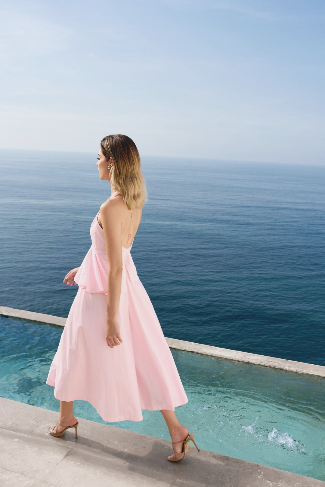 A model wearing a baby pink flowy dress with ruffles by Monica Arguedas.