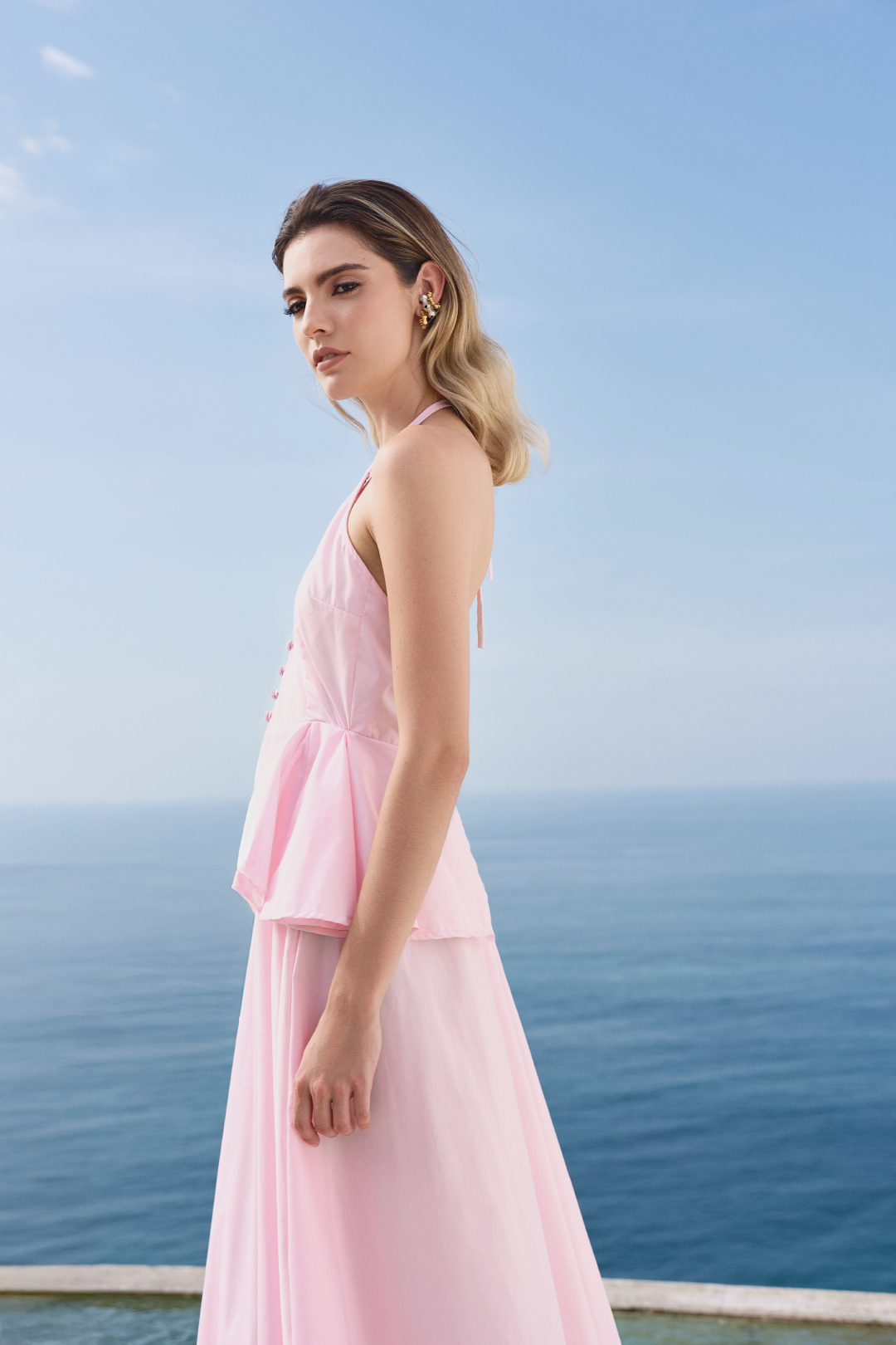 A model wearing a baby pink flowy dress with ruffles by Monica Arguedas.