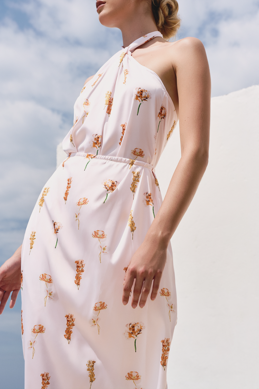 A model wearing a white floral twisted top and skirt with a slit by Monica Arguedas