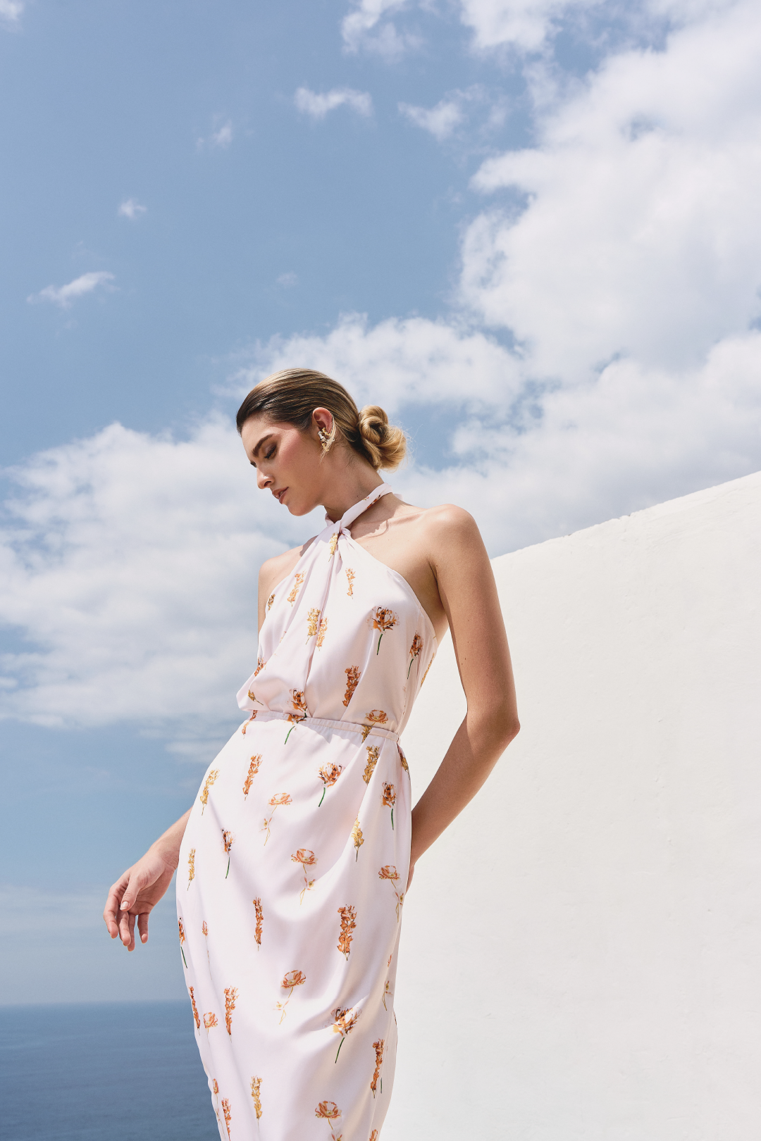 A model wearing a white floral twisted top and skirt with a slit by Monica Arguedas