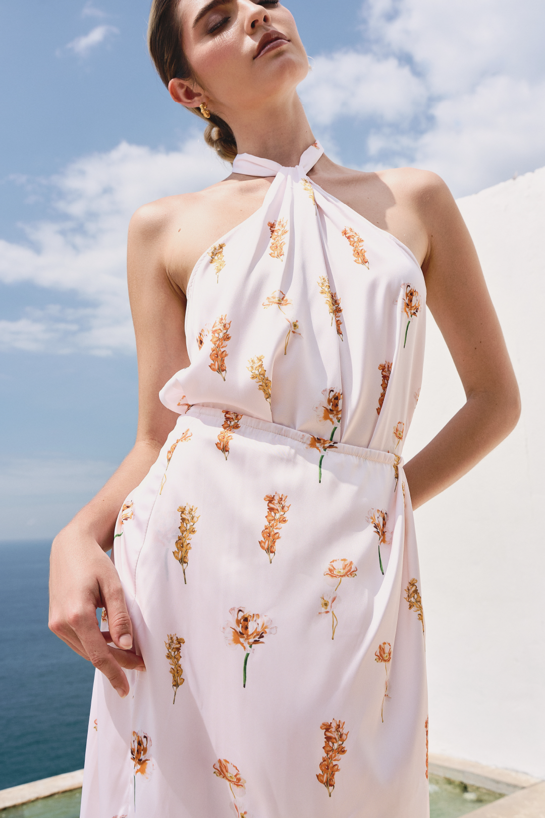 A model wearing a white floral twisted top by Monica Arguedas