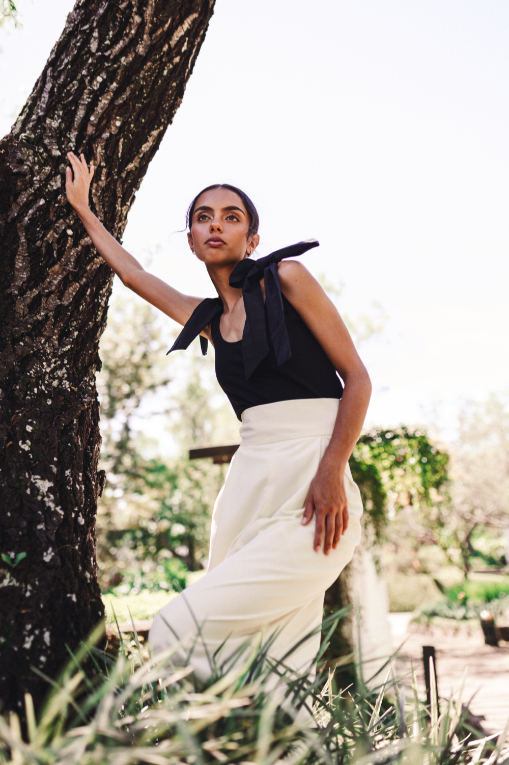 Model wearing a top solid black with bows on the shoulders in a salvadoran forest.