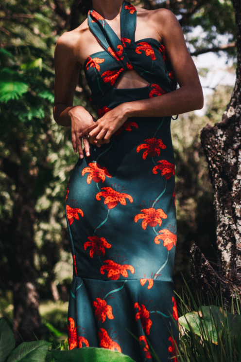 Model wearing a dark green handmade dress by Monica Arguedas, printed with blooming orange flowers.