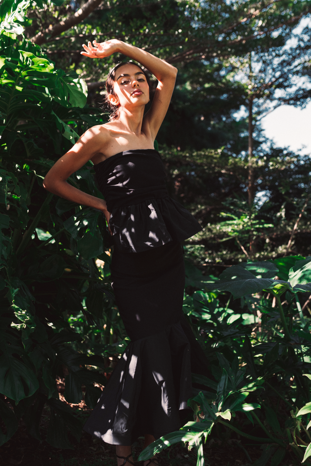 Model wearing a set with a sleeveless black top and a midi solid black skirt with stirs surrounded by a salvadoran forest.
