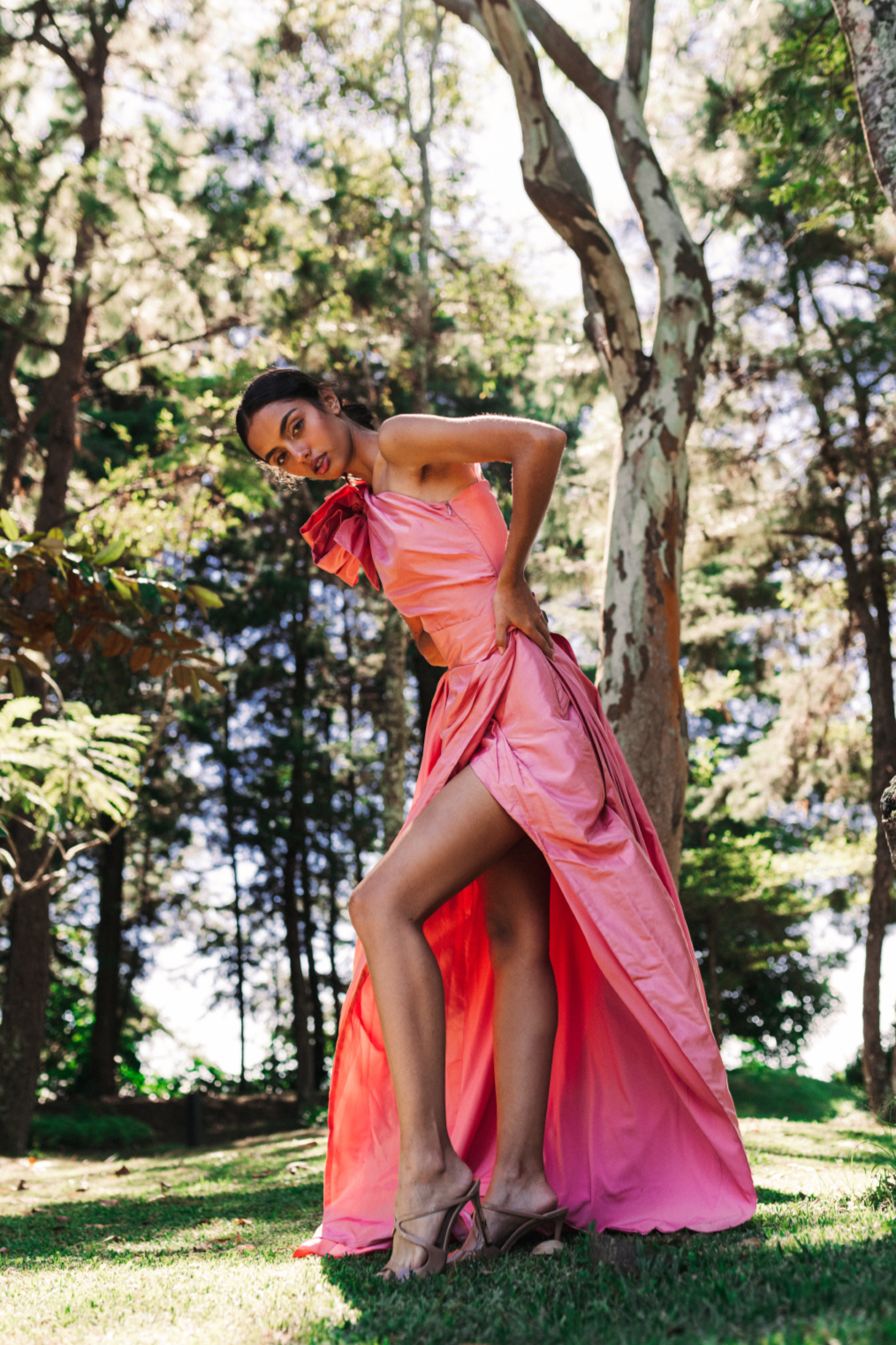 Model wearing a flowing pink handmade dress by Monica Arguedas in a lush Salvadoran forest.