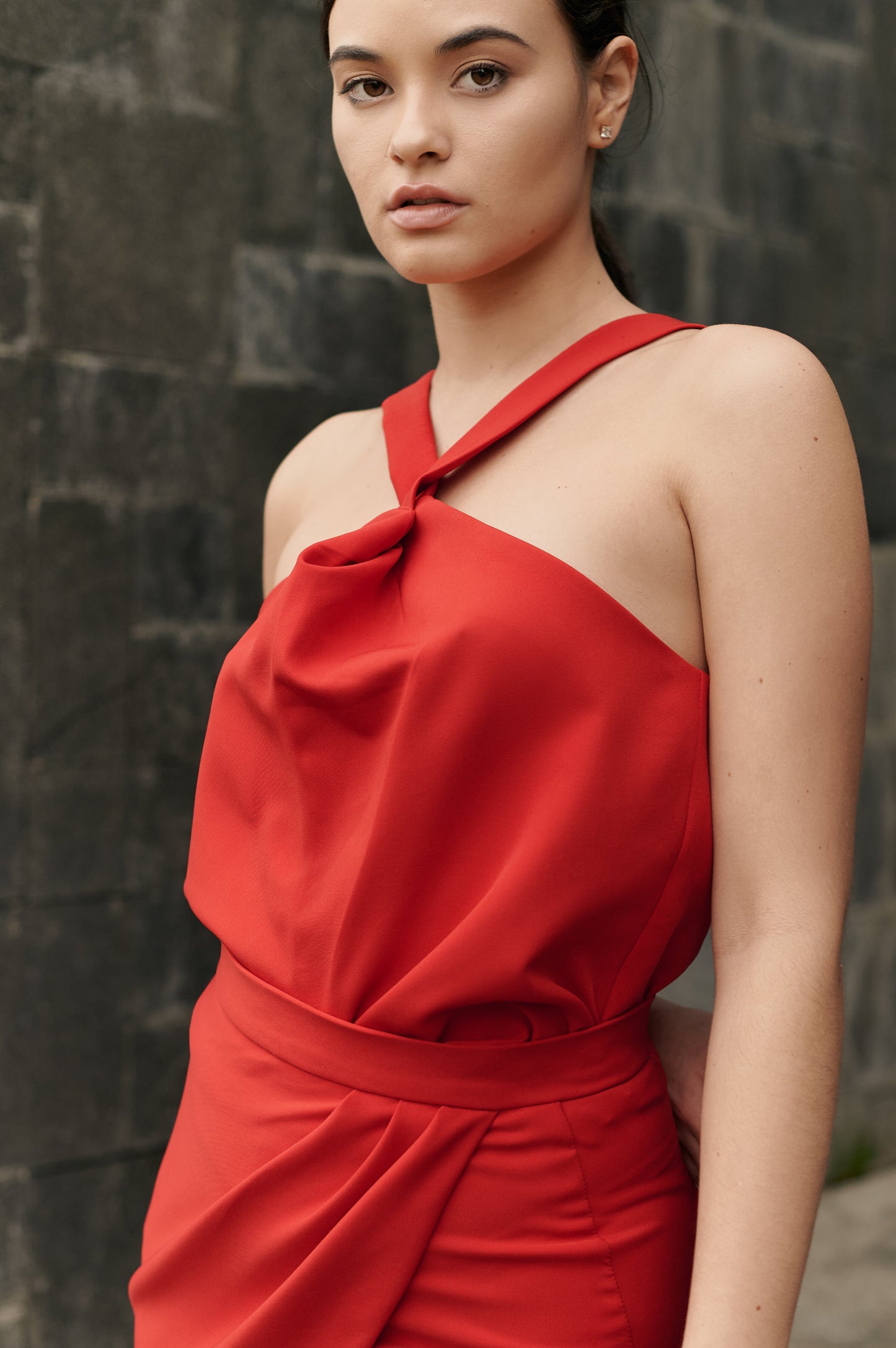A model wearing a red twisted top by Monica Arguedas.