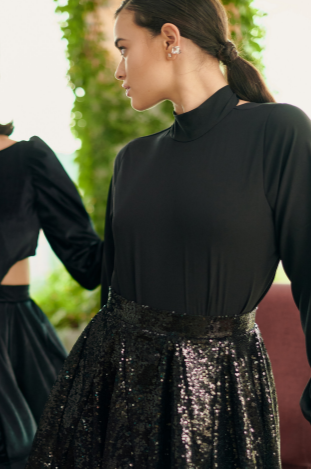 A model wearing a flowy black top and long sleeves by Monica Arguedas.