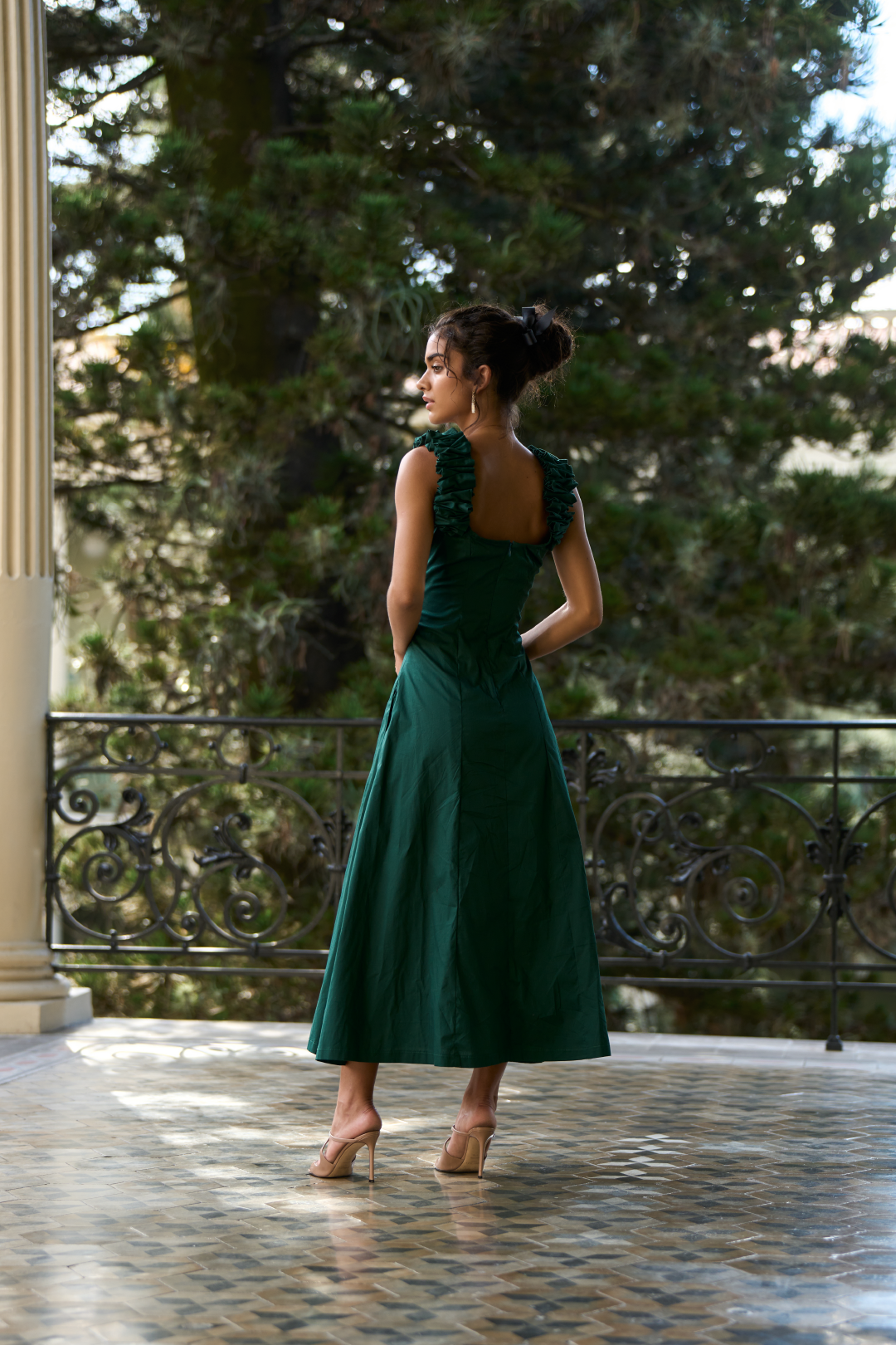 A model wearing a green dress with scrunched straps and a slit by Monica Arguedas.