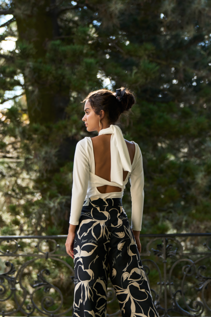 A model wearing a creme bodysuit with a crossed neckline and open back by Monica Arguedas.