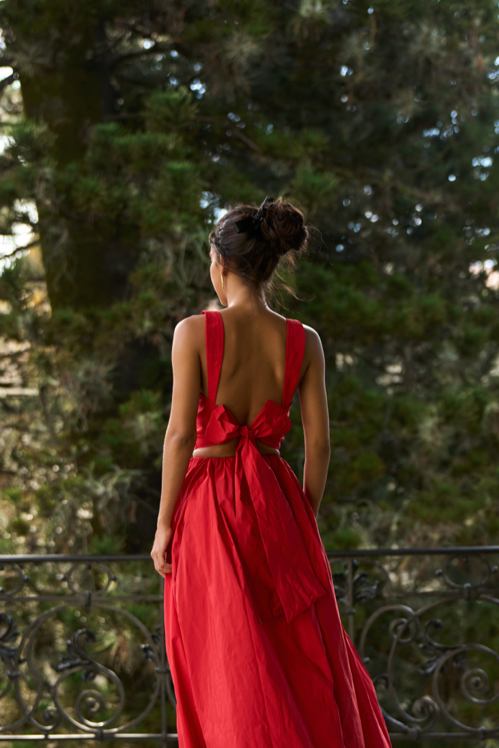 A model wearing a red top with a bow on the back by Monica Arguedas.