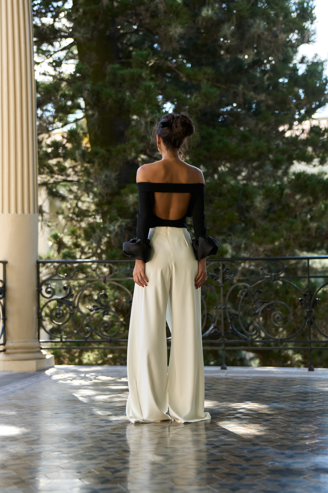 A model wearing a black off the shoulder bodysuit with puffy cuffs by Monica Arguedas.