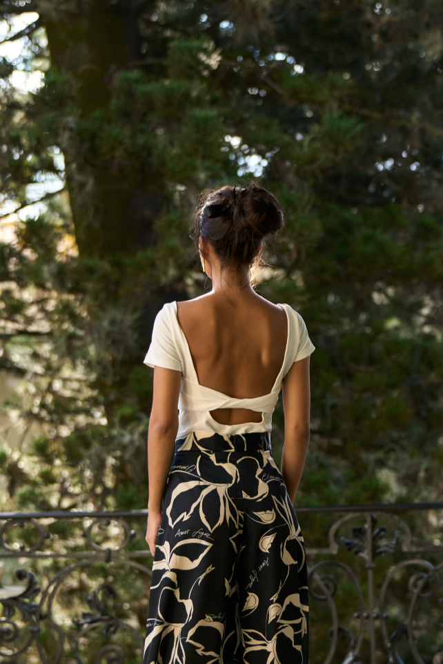 A model wearing a white backless bodysuit by Monica Arguedas.