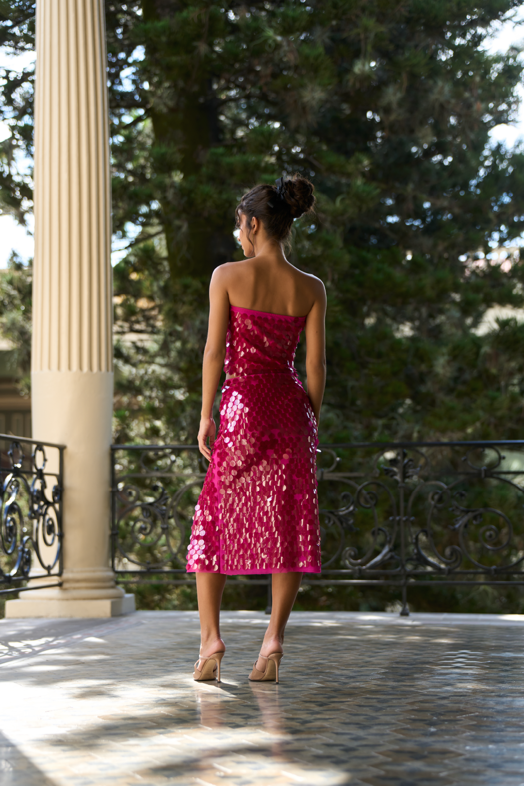 A model wearing a bright pink sequin skirt with a slit on the side by Monica Arguedas.