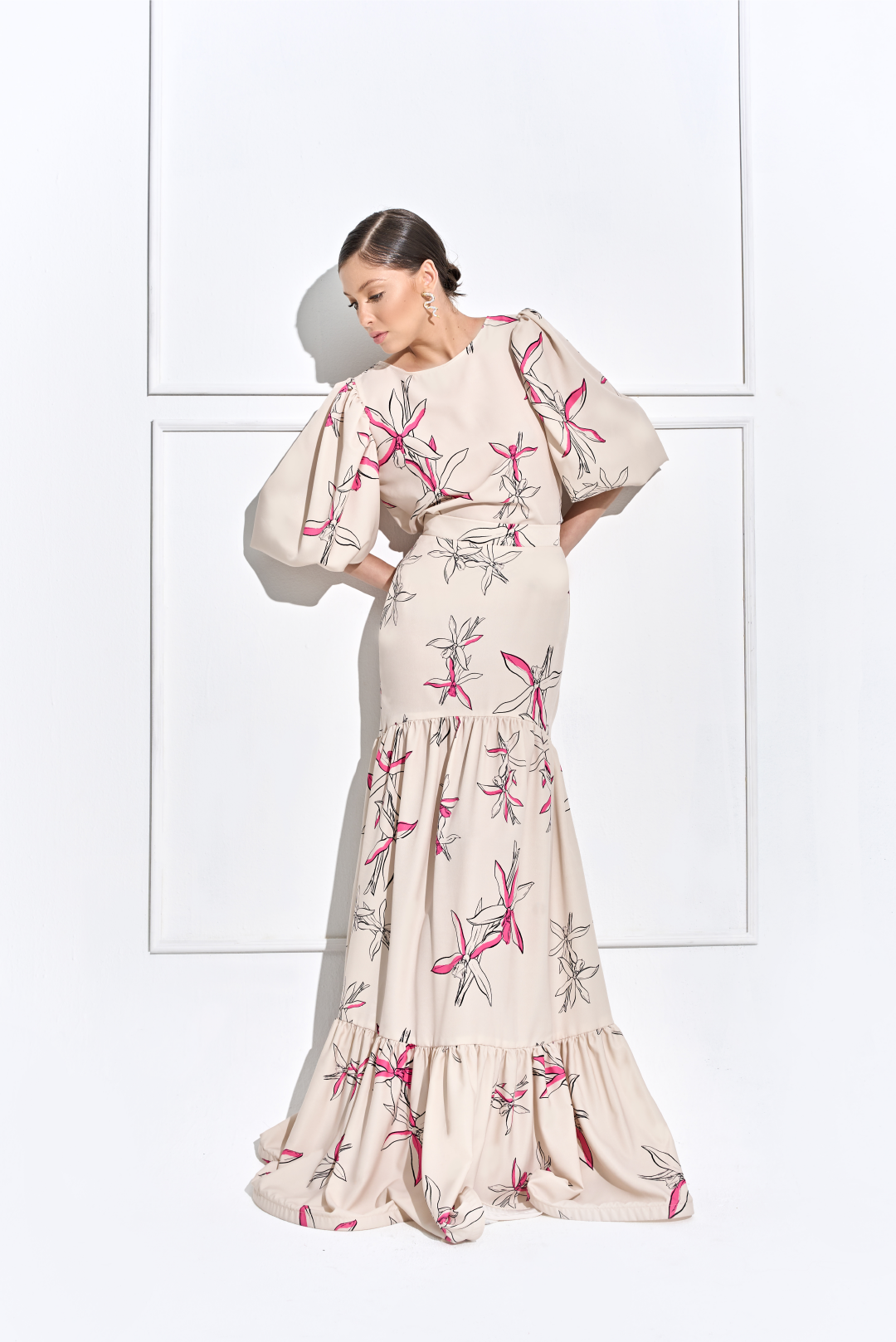 Model wearing a puffed sleeve creme with black and pink flower print top by Monica Arguedas.