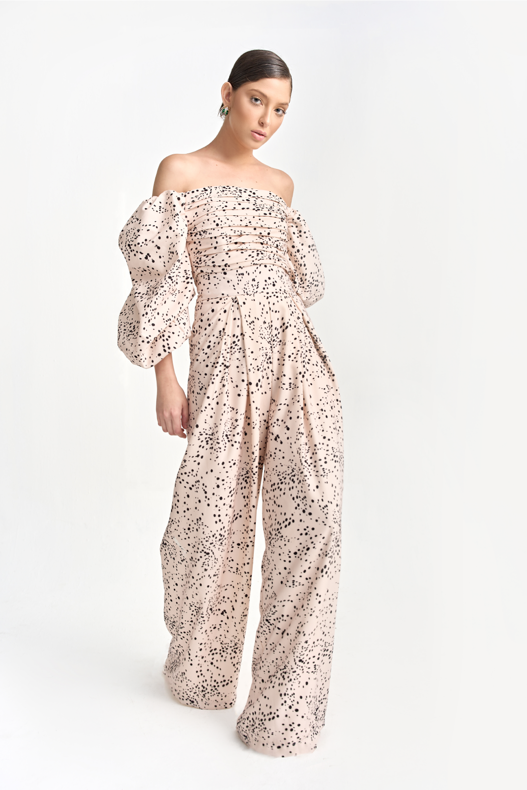 A model wearing an off the shoulder creme top with black dots and long puffy sleeves by Monica Arguedas.