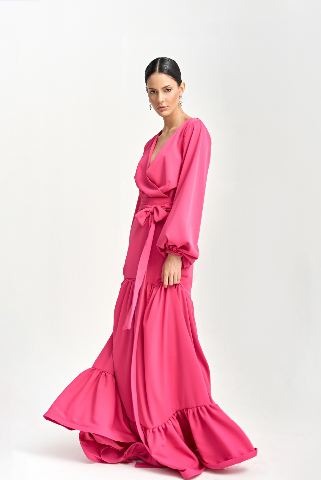 A model wearing a overlapped bright pink top with long sleeves by Monica Arguedas.