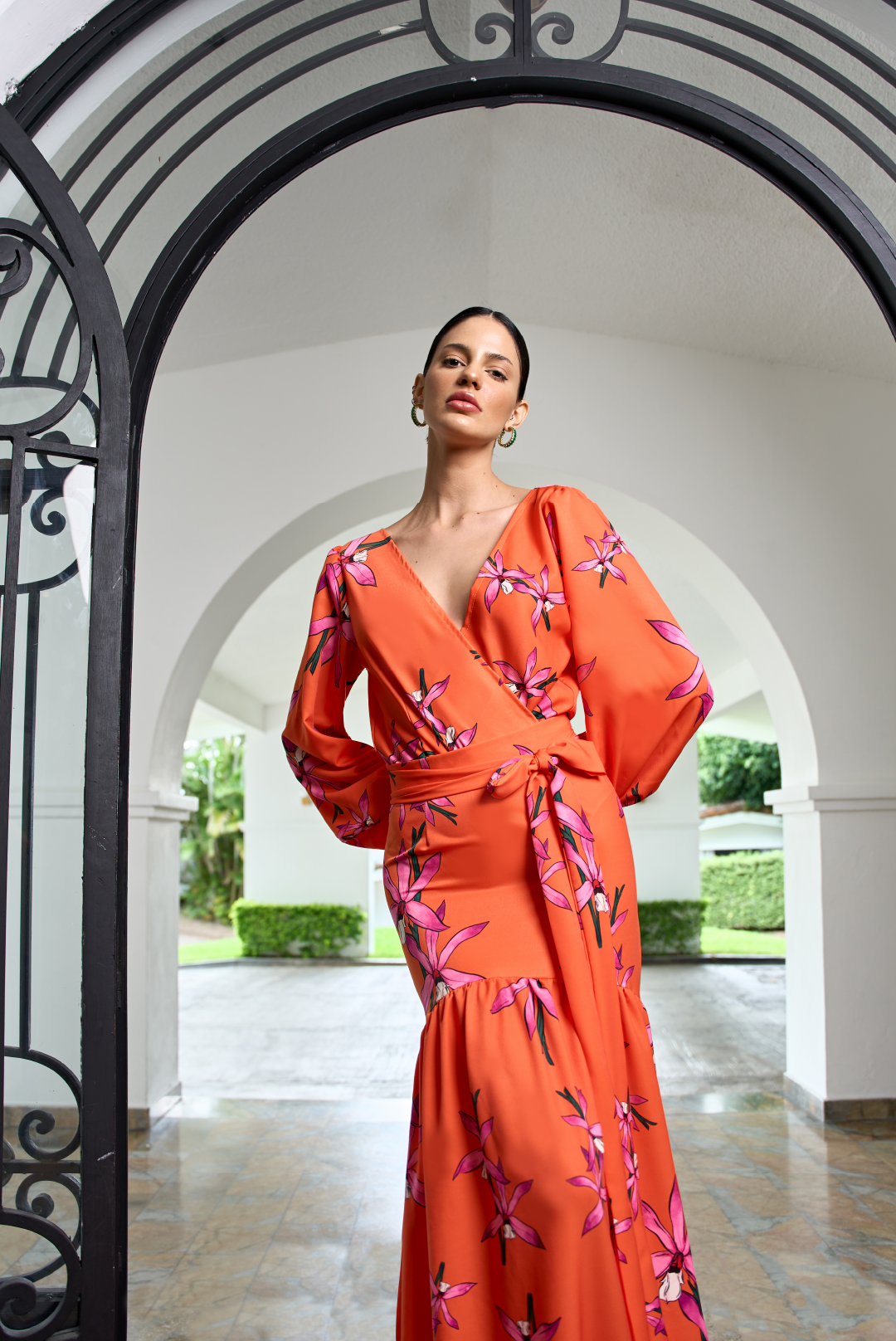 Model wearing a drapped bodysuit with long sleeves with a pink flower print by Monica Arguedas.