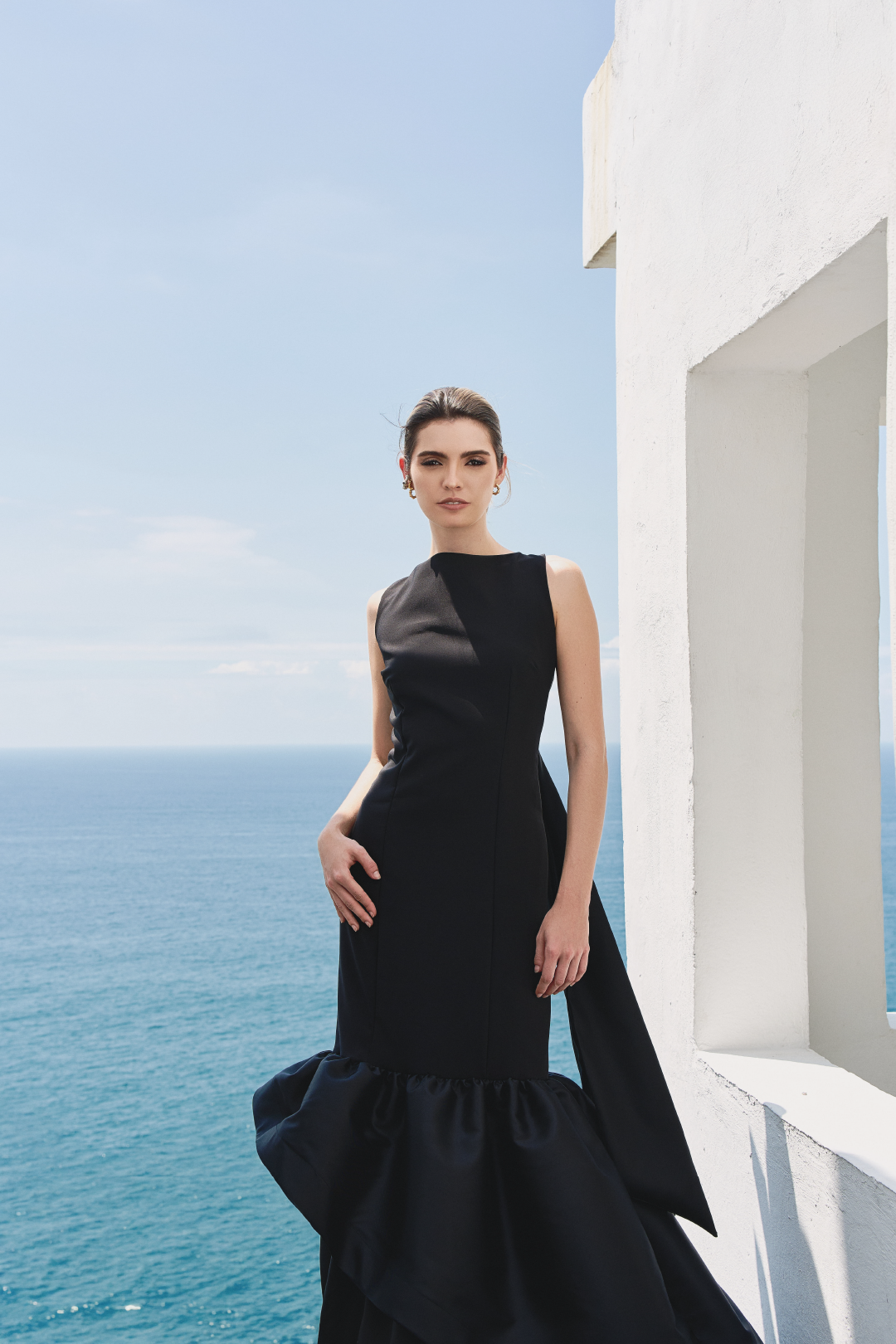 A model wearing a solid black dress with ruffles by Monica Arguedas.