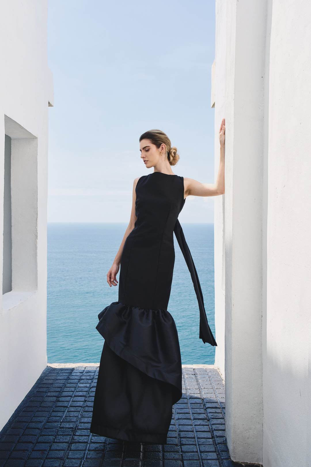 A model wearing a solid black dress with ruffles by Monica Arguedas.