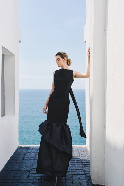 A model wearing a solid black dress with ruffles by Monica Arguedas.