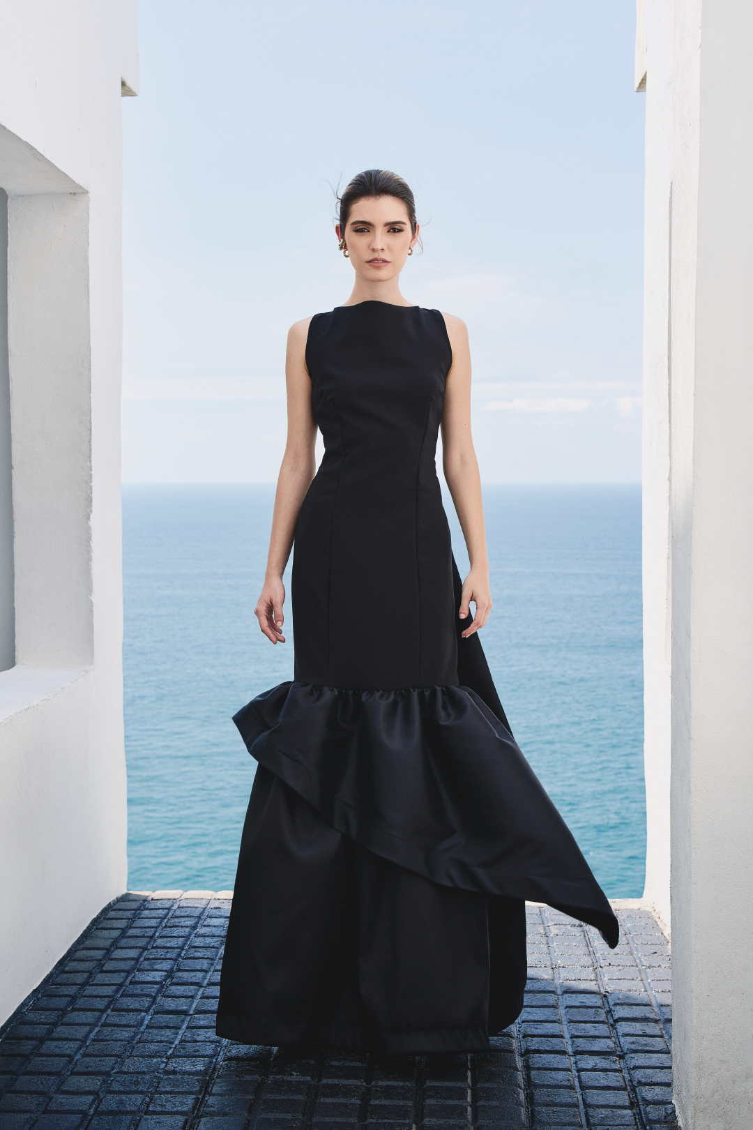A model wearing a solid black dress with ruffles by Monica Arguedas.