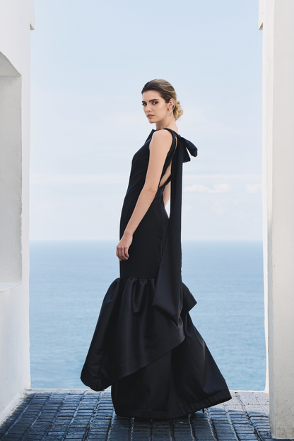 A model wearing a solid black dress with ruffles by Monica Arguedas.
