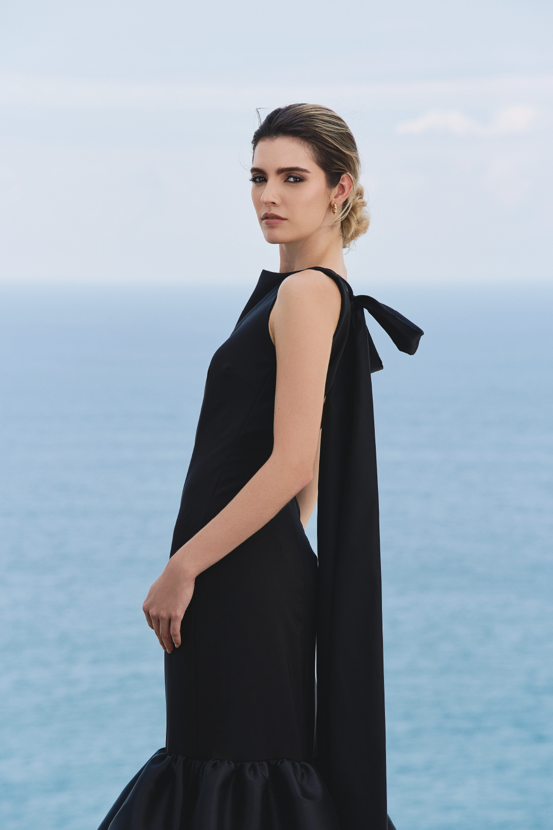 A model wearing a solid black dress with ruffles by Monica Arguedas.