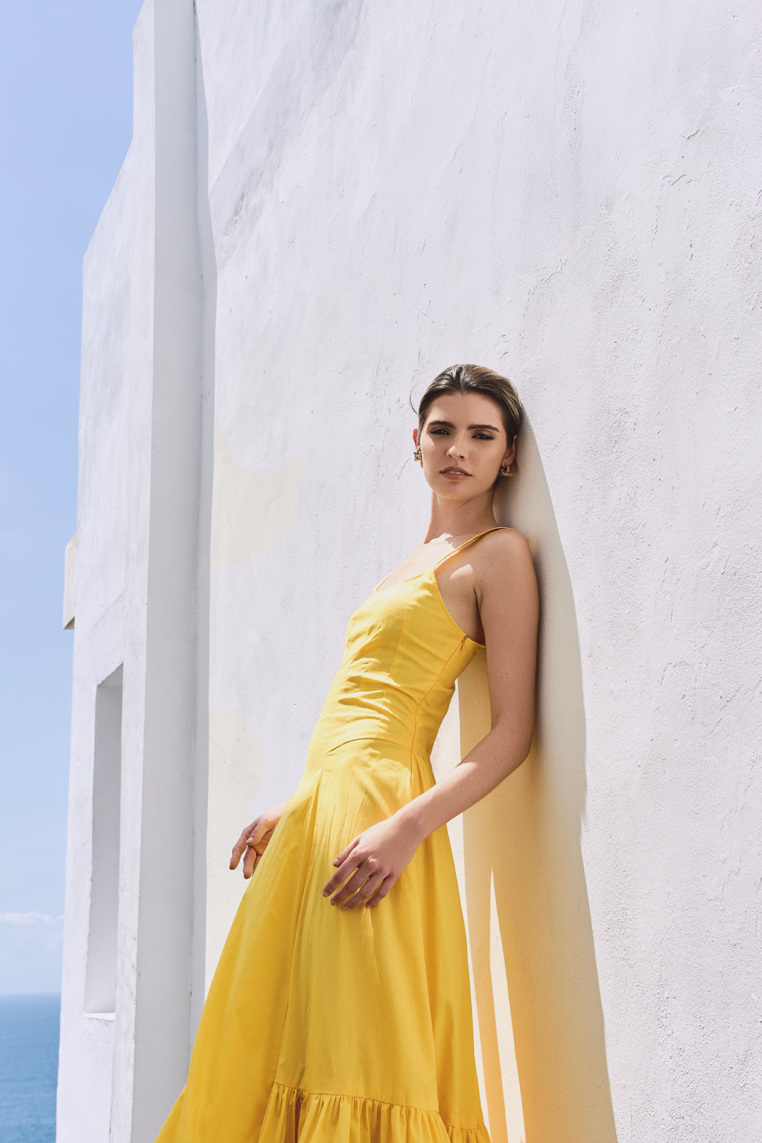 A model wearing a solid yellow dress with ruffles on the bottom by Monica Arguedas