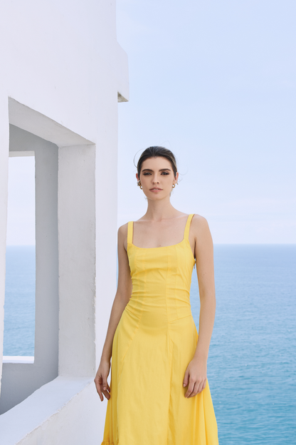A model wearing a solid yellow dress with ruffles on the bottom by Monica Arguedas