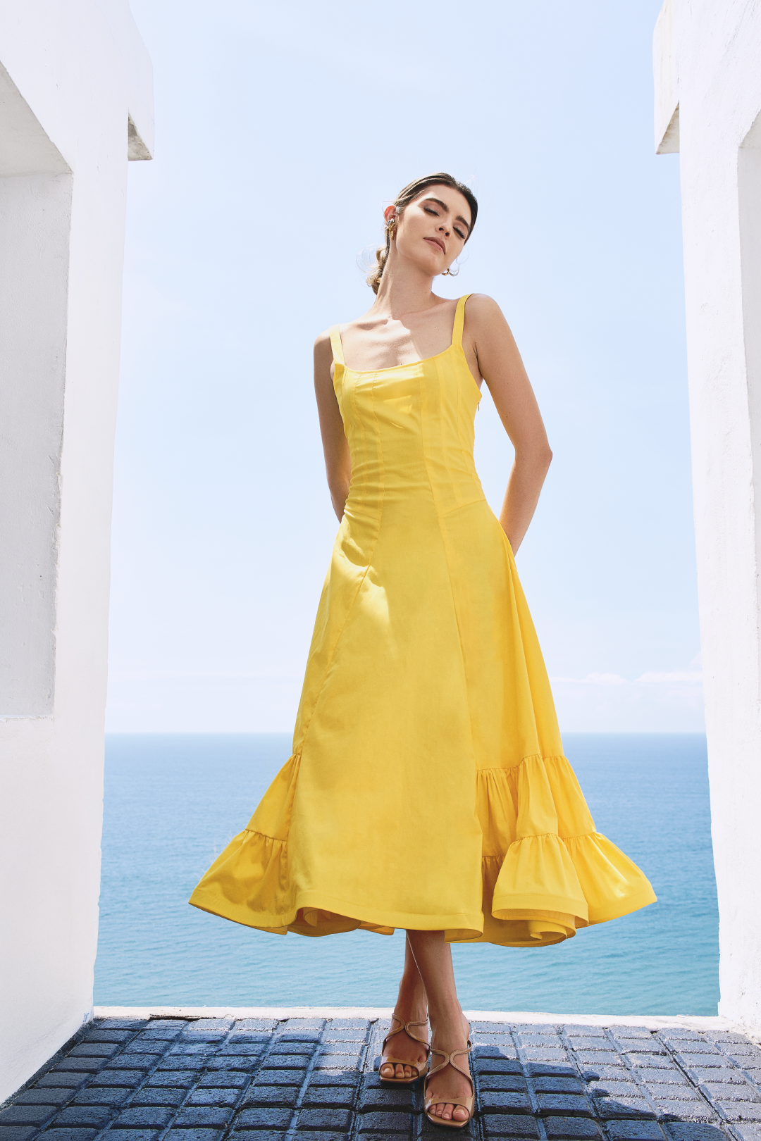A model wearing a solid yellow dress with ruffles on the bottom by Monica Arguedas