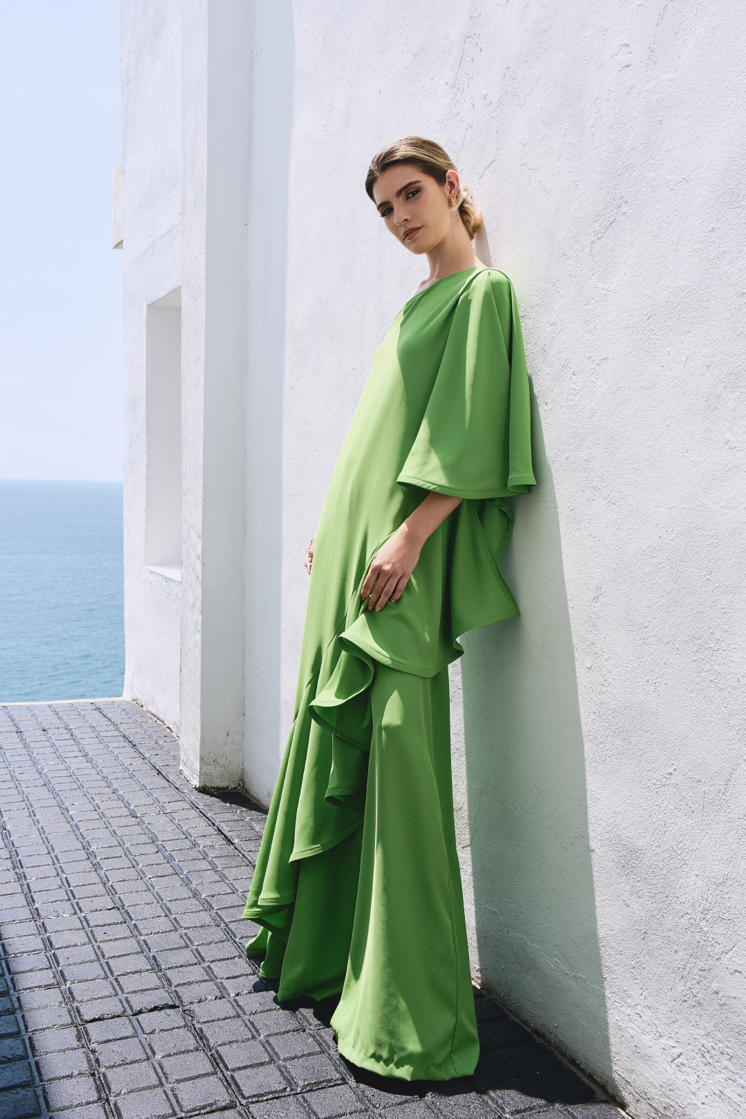 A model wearing a solid green flowy set by Monica Arguedas.