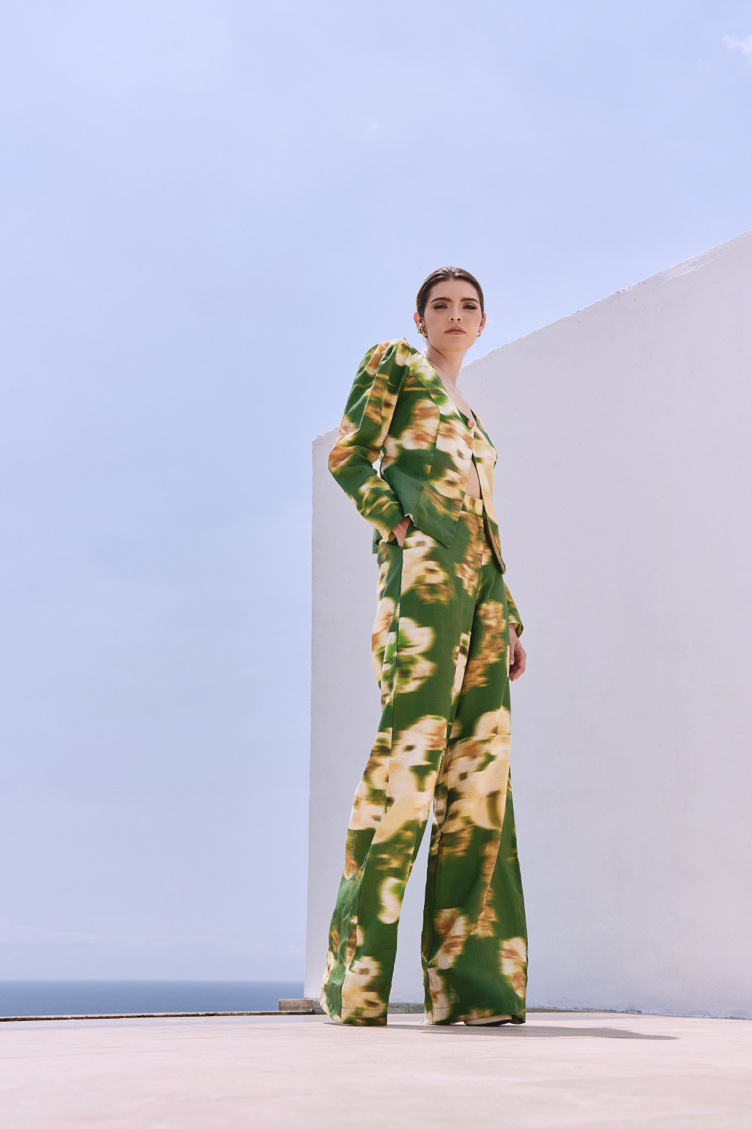 A model wearing green pants with a blurred floral print by Monica Arguedas