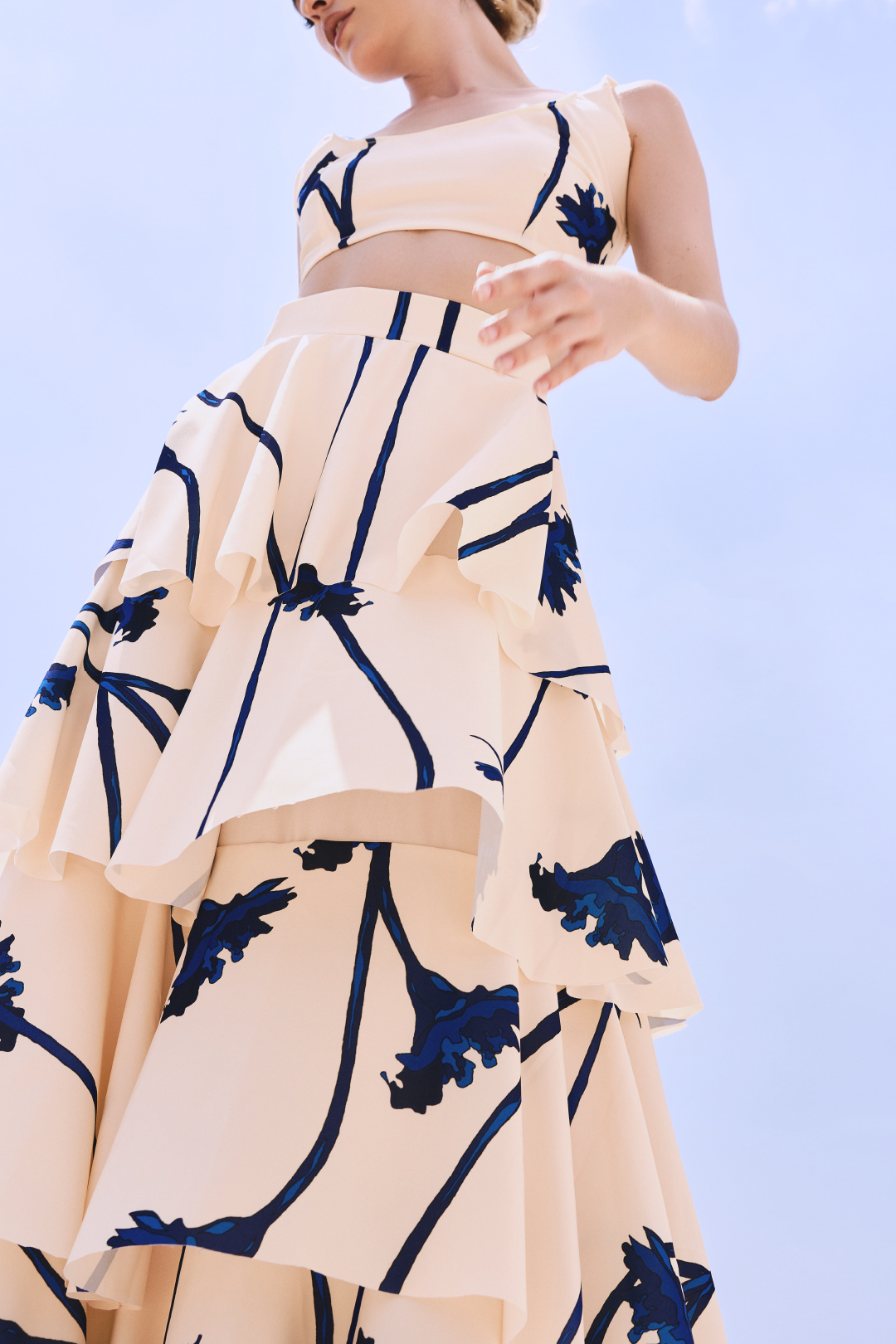 A model wearing a cream ruffled skirt with blue flowers by Monica Arguedas