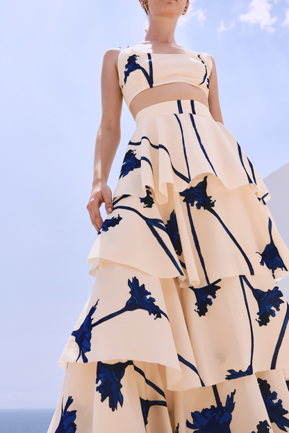 A model wearing a cream ruffled skirt with blue flowers by Monica Arguedas