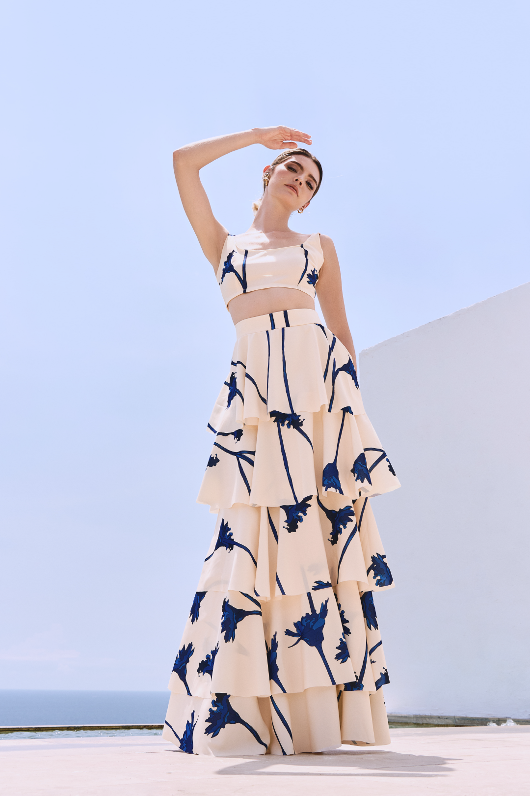 A model wearing a cream ruffled skirt with blue flowers by Monica Arguedas