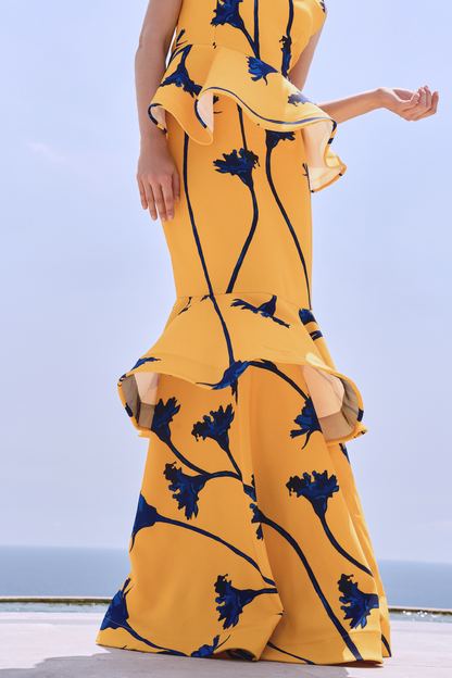A model wearing a yellow skirt with blue flowers and ruffles by Monica Arguedas