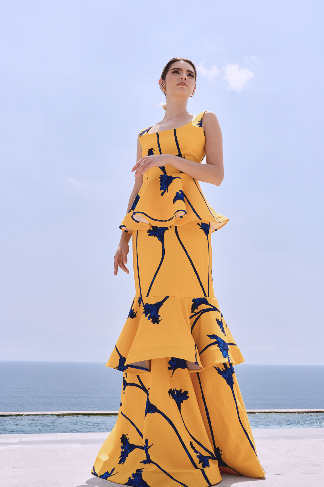 A model wearing a yellow skirt with blue flowers and ruffles by Monica Arguedas