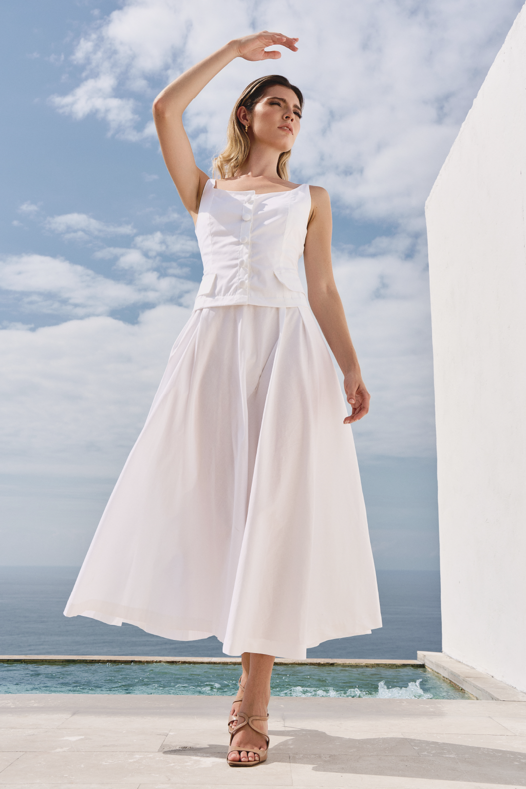 A model wearing a solid white dress with a flowy bottom by Monica Arguedas