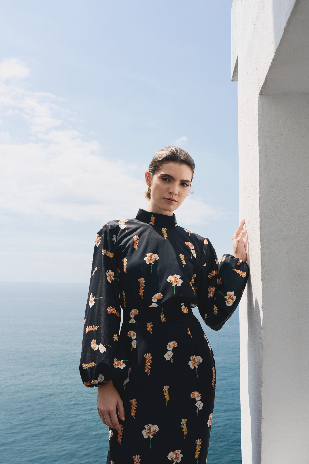 A model wearing a black long-sleeve top with floral print and open back by Monica Arguedas
