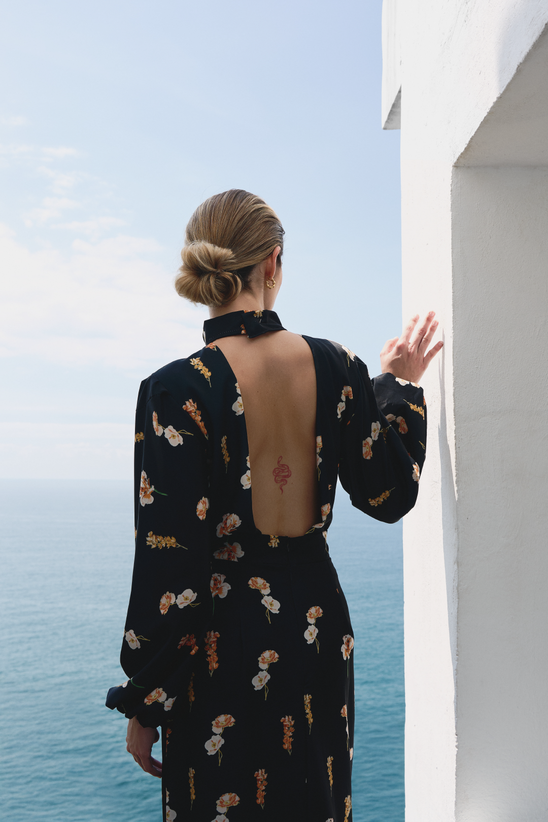 A model wearing a black long-sleeve top with floral print and open back by Monica Arguedas