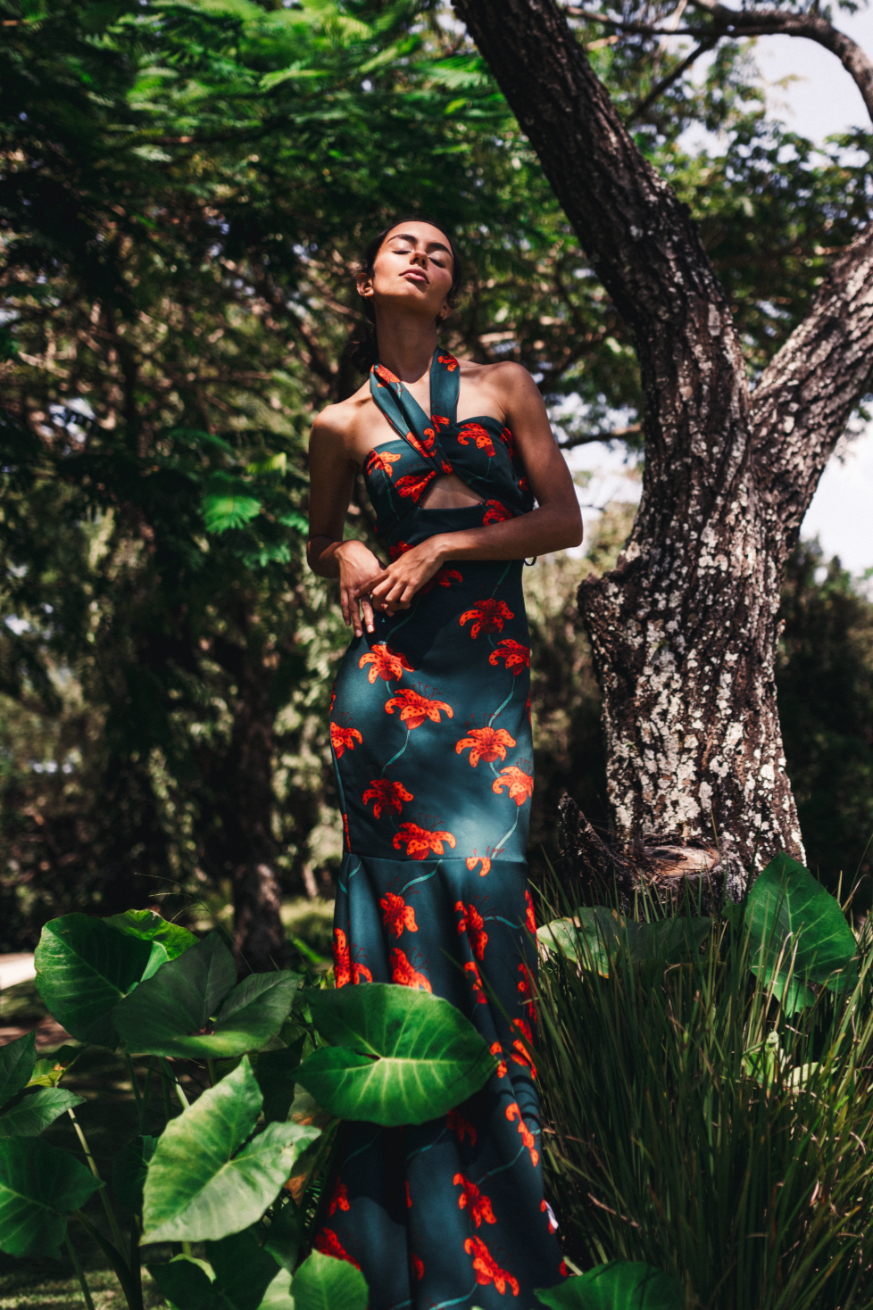 Model wearing a dark green handmade dress by Monica Arguedas, printed with blooming orange flowers.