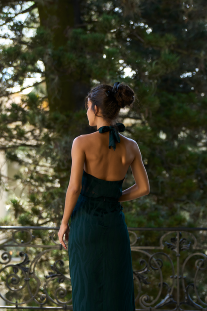 A model wearing a green halter top with an open back by Monica Arguedas.